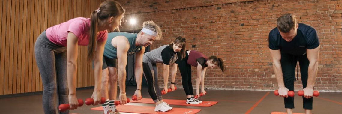Fitness group performing exercises with dumbbells in a modern yoga studio setting.
